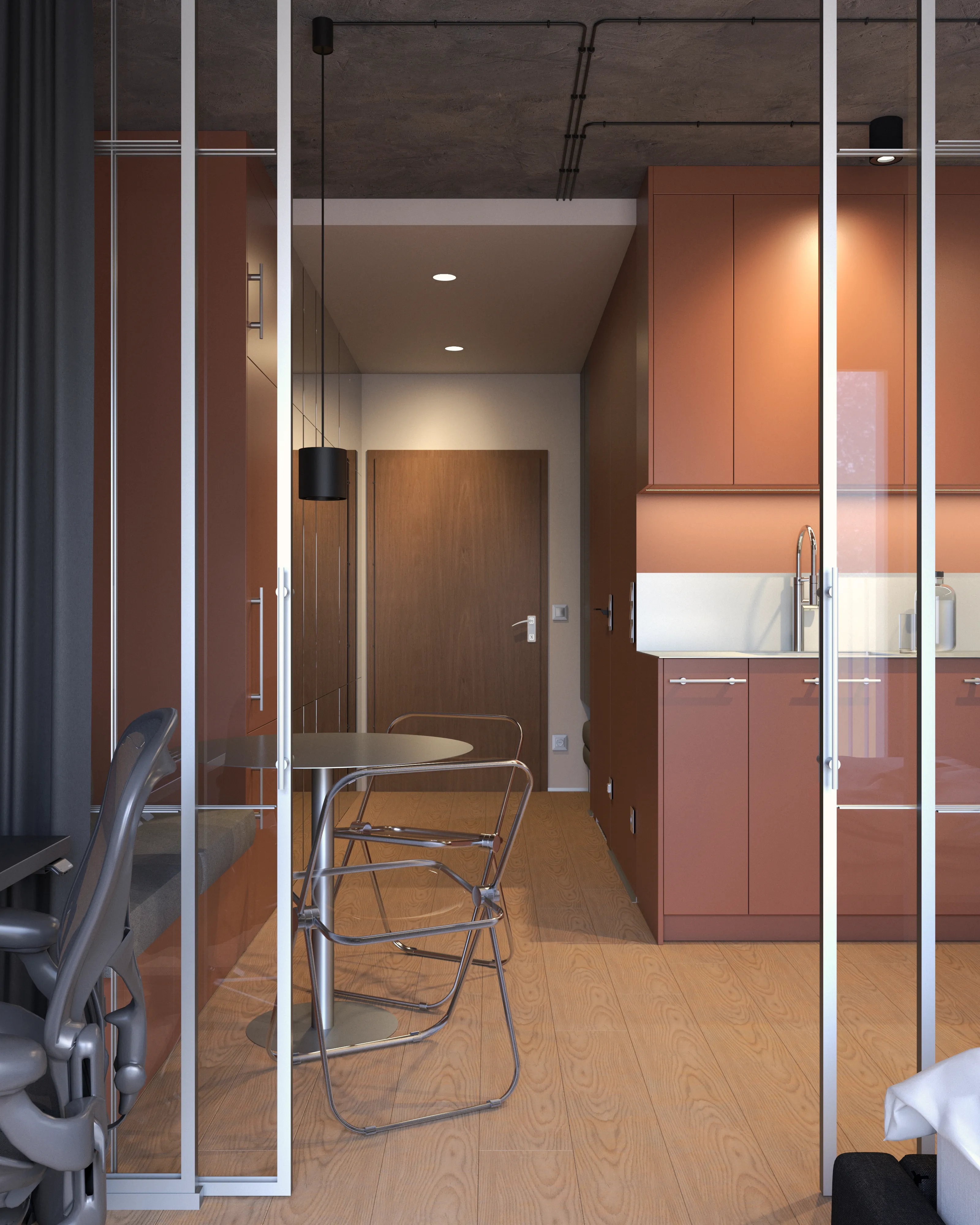 Jadalnia z metalowymi składanymi krzesłami – widok przez szklaną ściankę na aneks kuchenny w terrakocie, mała kawalerka w Warszawie, projekt Nalalab.